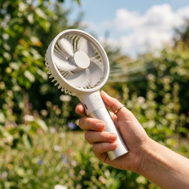 Portable hand fan being used outdoors on a warm day